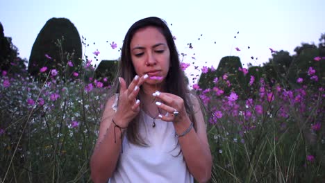 young latin woman enjoying nature ans smelling a flower in the middle of a beautiful purple field with tinny flowers