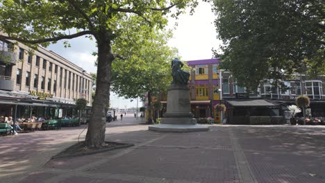 sunny day in zaandam's town square with a statue, colorful buildings, and leafy trees