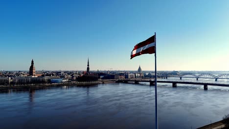 flag of latvia flying over a city riga