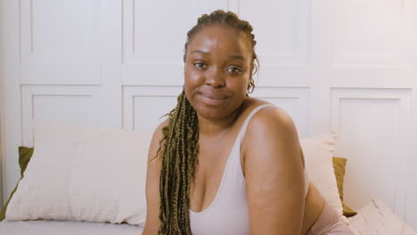 woman in underwear sitting on the bed looking at camera