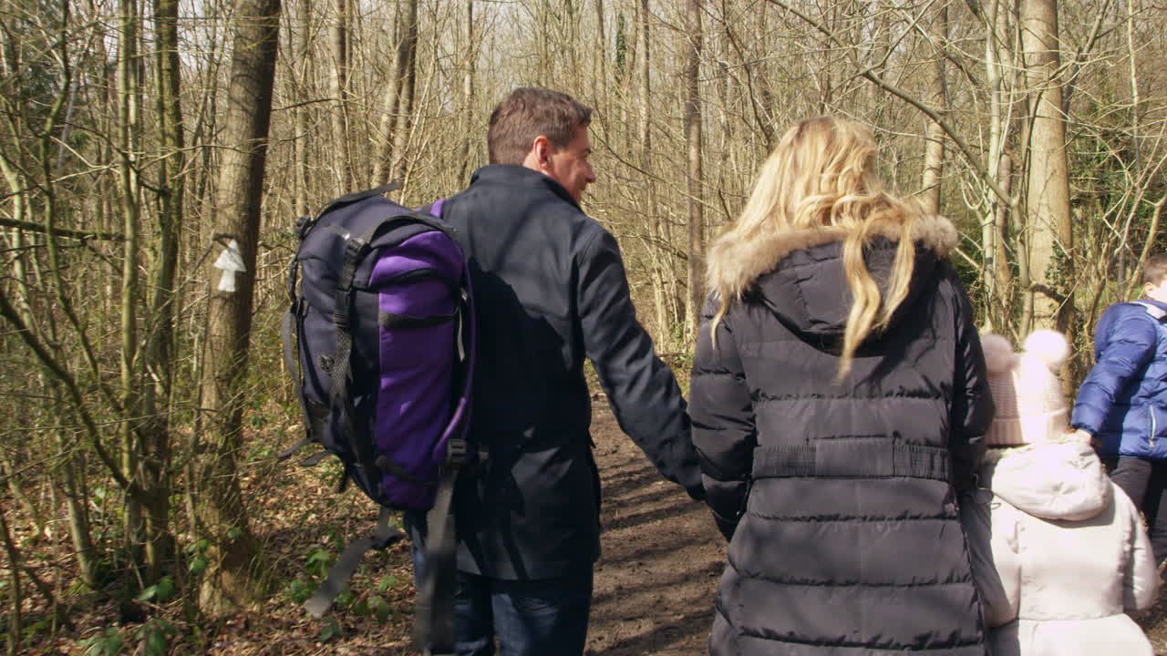Vierköpfige Familie und Familienhund spazieren durch den Wald, handgehalten, aufgenommen mit R3D.