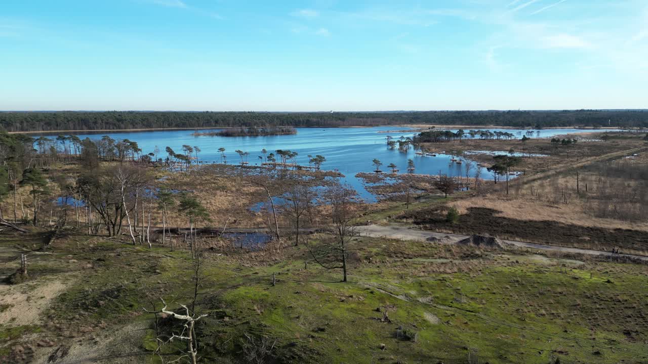 kalmthoutse heide dron volando directamente sobre los humedales y pasando sobre el agua, viendo a una persona caminando por el camino