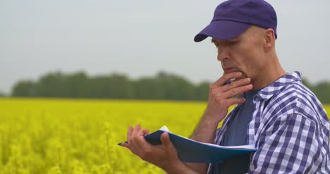 agricultor tomando notas en el campo de colza