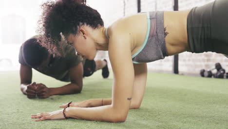 dos personas haciendo planking mientras trabajan en el gimnasio