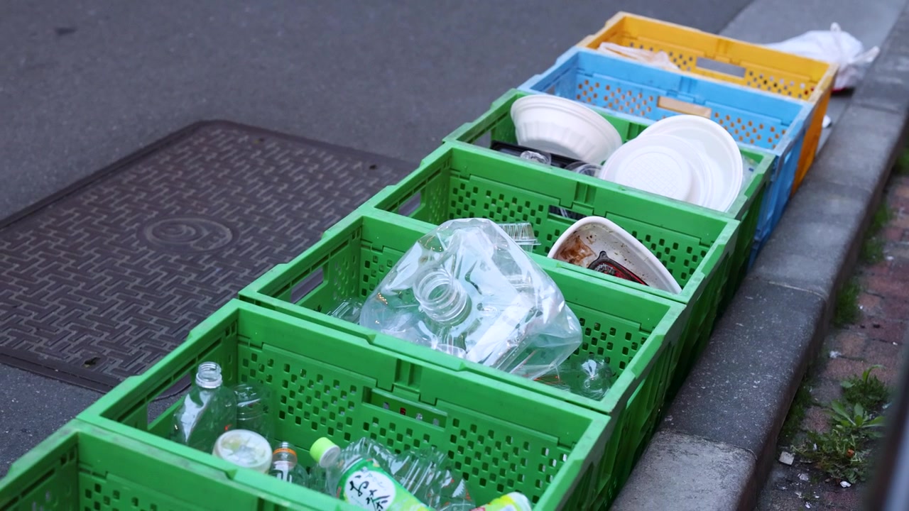 Static high-angle shot of sorted plastic waste in colorful crates on a Tokyo street.