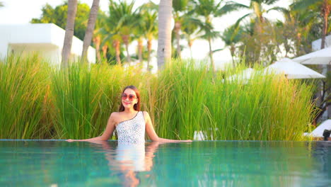 A-pretty-young-woman-leans-against-the-edge-of-a-swimming-pool