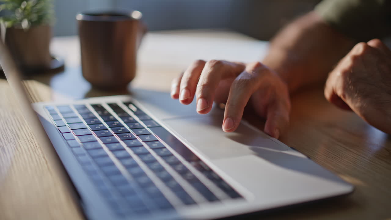Freelancer hand swiping laptop touchpad in sunshine remote workplace closeup