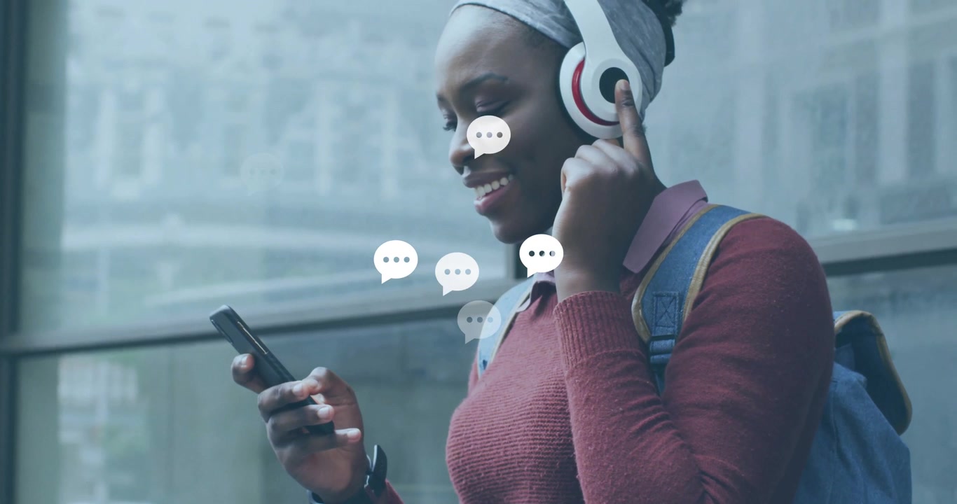 Una donna che cammina in un corridoio di vetro si ferma e riceve messaggi, mostrando bolle di chat tramite la tecnologia dello smartphone.