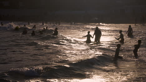 people enjoying the waves at the beach at sunset