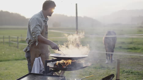 man grilling outdoors by a farm