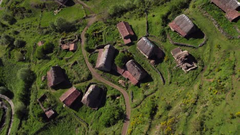 Aerial-tilt-up-view-of-Pornacal-Braña-hut-cabin-rural-village-in-Somiedo-valley,-Asturias