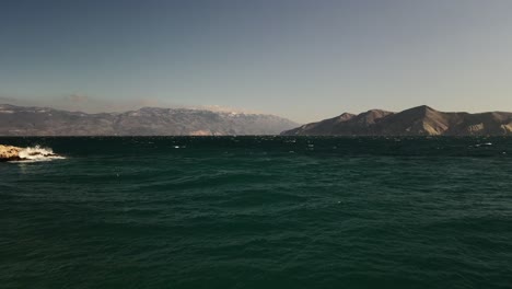 Plano-Recto-Sobre-El-Mar-Adriático-Con-Drones-En-Una-Costa-De-Baska-En-Croacia-Hermosos-Colores-Cielo-Azul-Grandes-Montañas