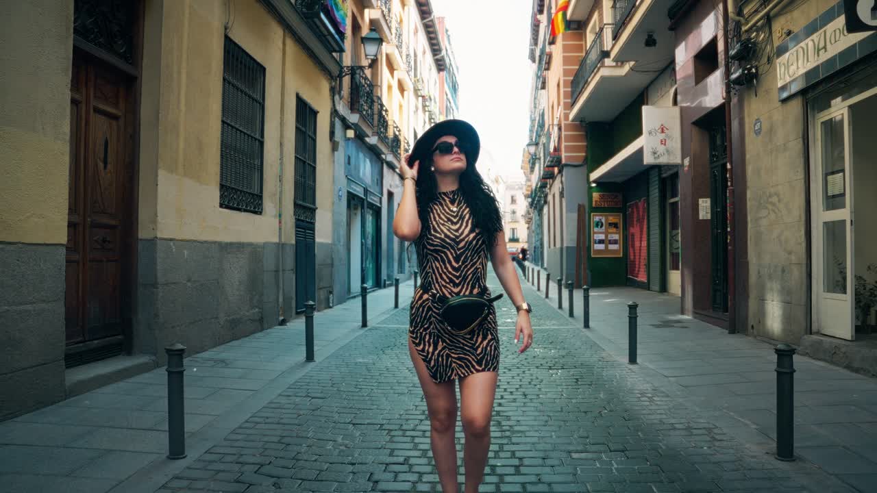 Girl walking down side street, of big city, looking around, happy and smiling, chetah dress, hat and glasses on
