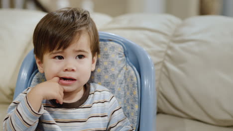 two years old, the baby scratches his teeth with his hand. the boy cuts milk teeth