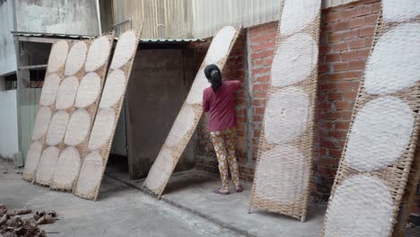 woman of humble vietnamese family placing masses of banh trang cake