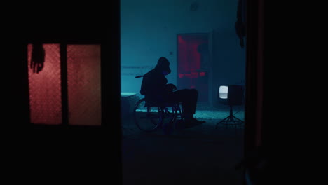 silhouette of a person in a wheelchair in a neon-lit abandoned room