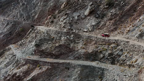 Red-jeep-driving-on-deadly-mountain-road-to-Fairy-Meadows,-Pakistan