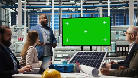 factory shareholders chat about company growth, looking at green screen monitor