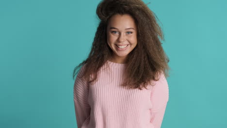 caucasian curly haired woman waving to the camera.