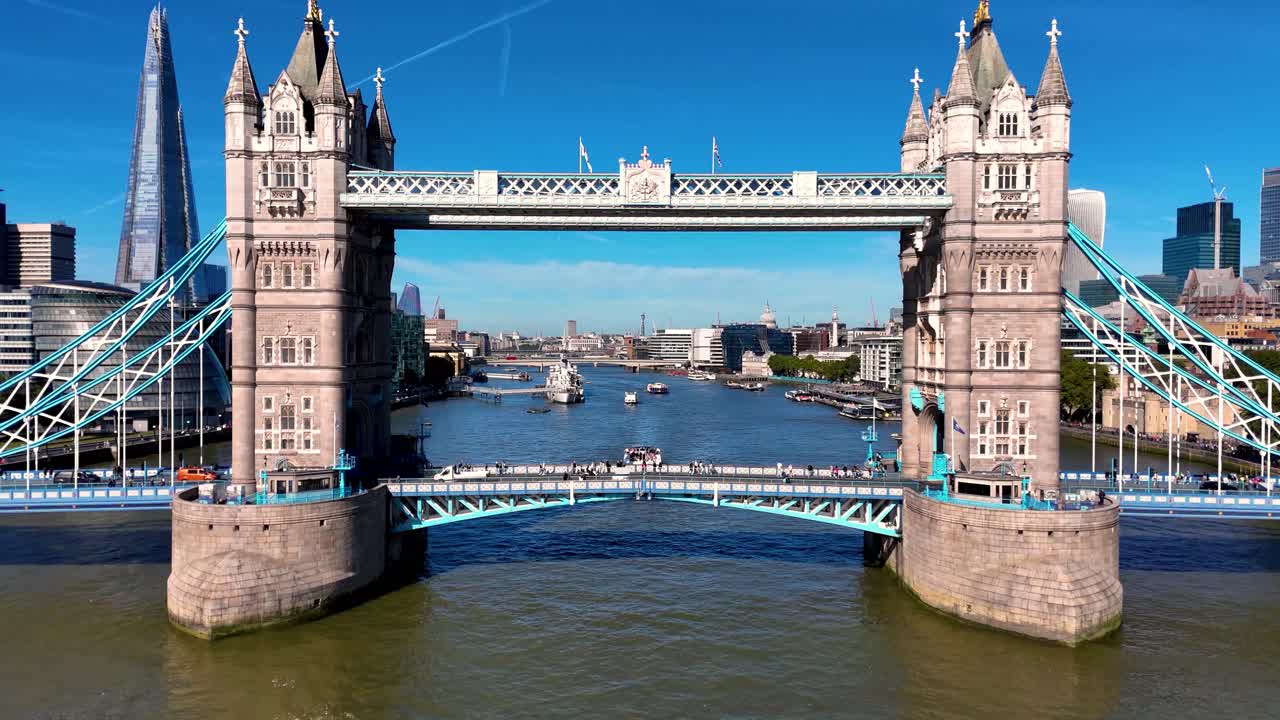 Experience a breath-taking aerial view as London's iconic Tower Bridge is slowly revealed, set against the majestic Thames, riverboats, and the stunning city skyline in this captivating video.