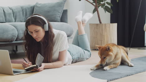 young woman working on her laptop at home next to her dog 3