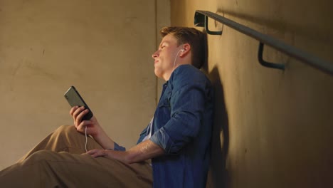 Young-man-listening-to-music-in-empty-warehouse