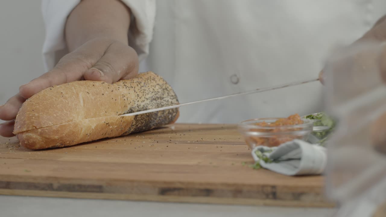 Man Cutting a Piece of Bread with a Knife in the Kitchen on a Sunny Day Shot on Red Camera