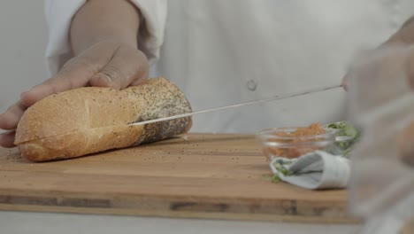 man cutting a piece of bread with a knife in the kitchen on a sunny day shot on red camera