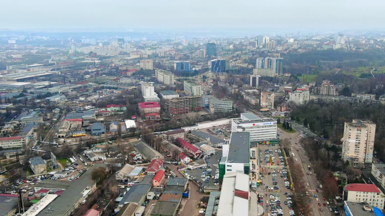Vista aérea con dron de Chisináu, hyperlapse. Vista panorámica de varios edificios, carreteras y aparcamientos con coches en movimiento y árboles desnudos. Clima nublado. Moldavia