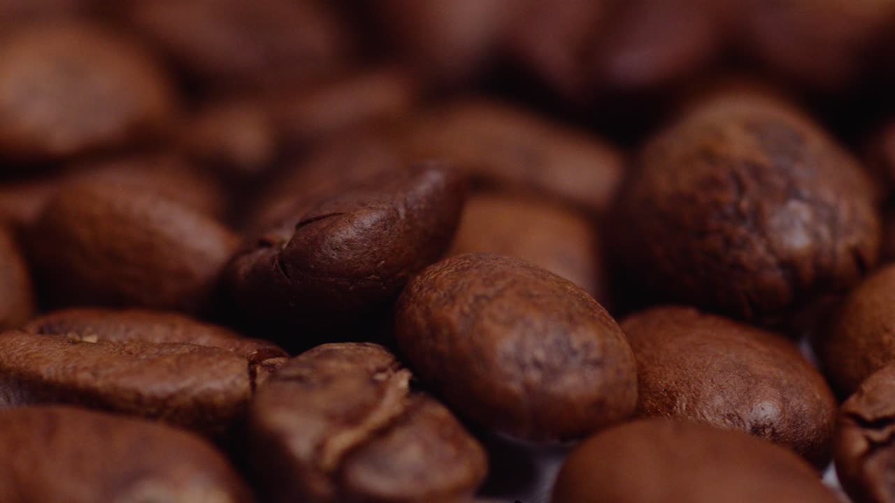Makro-nærbillede med glidende bevægelse af ristede kaffebønner i fokuseret belysning i et studie