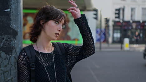 outdoor fashion portrait of young alternative style woman standing on london city street uk smoking hand rolled cigarette with busy road in background