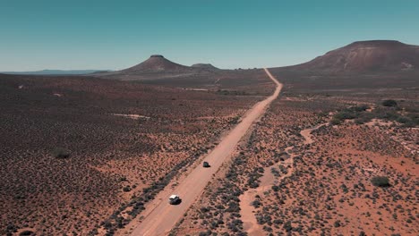 two cars drive in convoy over a vast landscape in the karoo of south africa