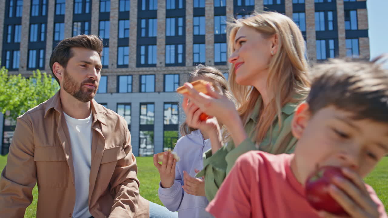 Happy people enjoying picnic on green grass sunny day closeup. Children eating