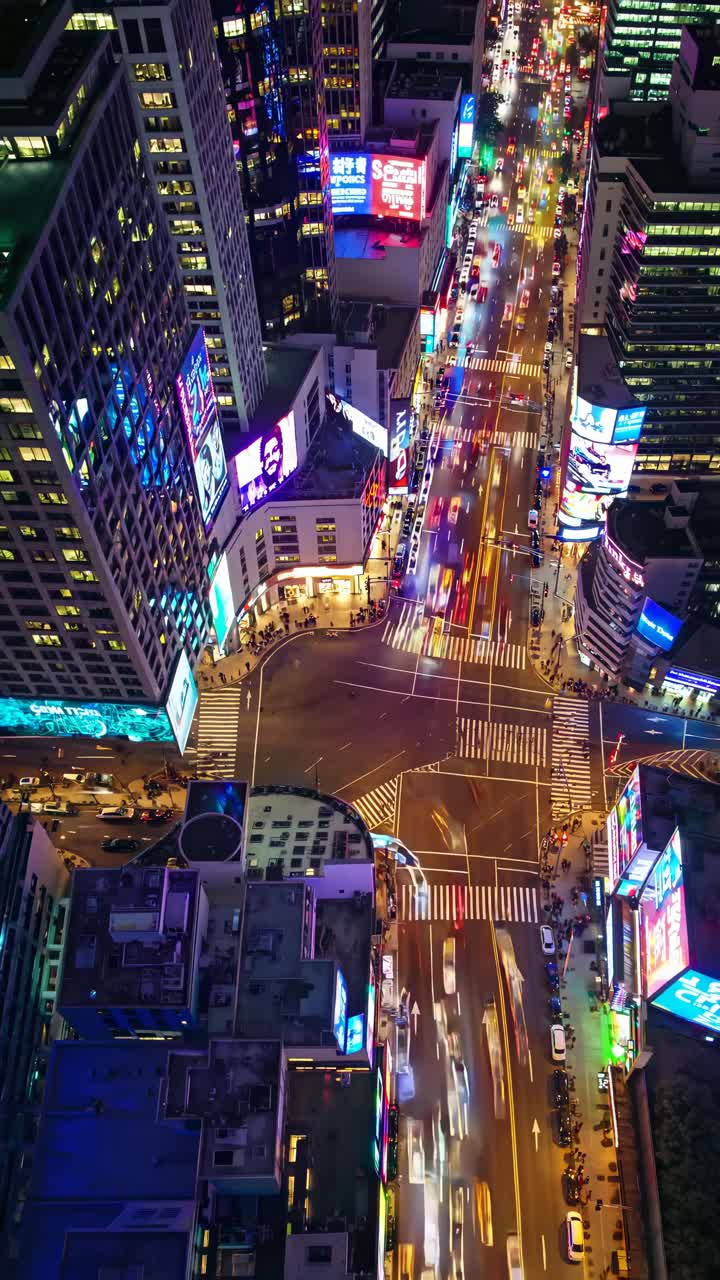 Aerial view of a bustling city intersection at night, showcasing vibrant lights and traffic