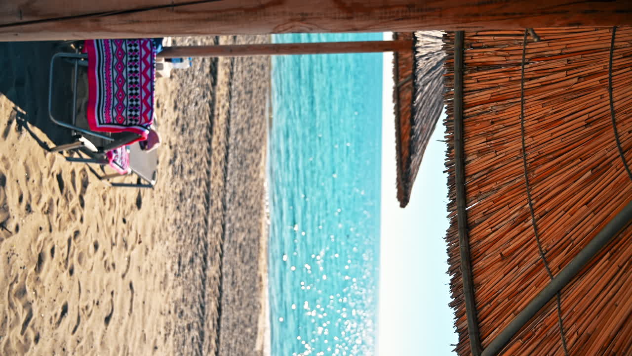 Spiaggia sulla costa dell'Egeo in Grecia. Lettino con vestiti, ombrellone, sabbia, mare blu