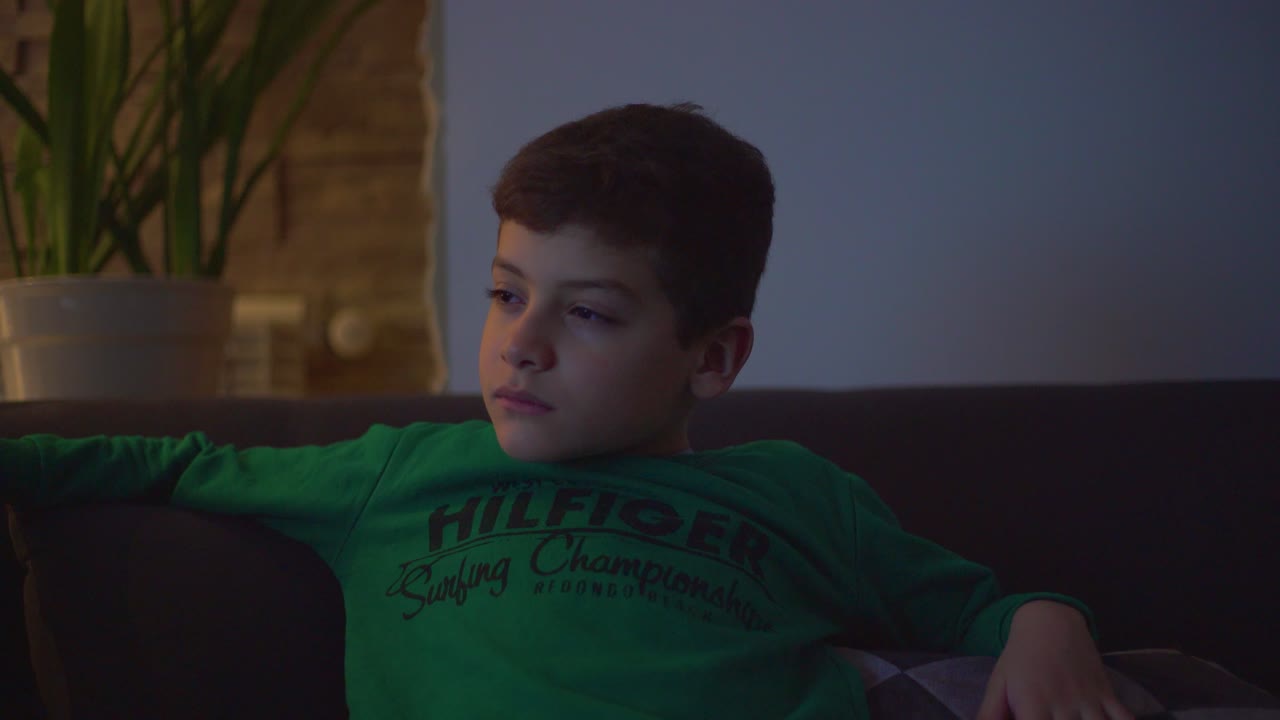 텔레비전 앞에서 피곤한 아이가 소파에서 잠들어 있습니다.