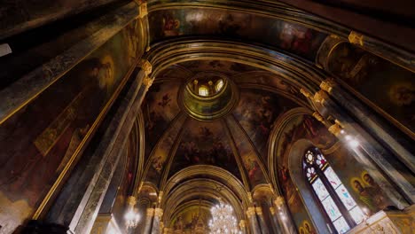 Revealing-wide-shot-of-a-gorgeous-interior-ceiling-in-a-eclectic-cathedral-showing-stained-glass-windows-and-chandelier