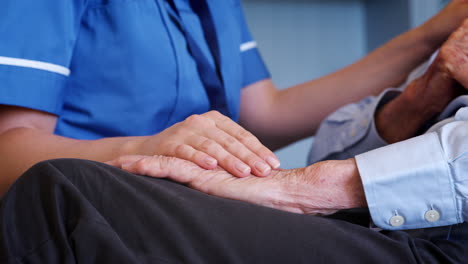 close up of nurse comforting senior man on home visit