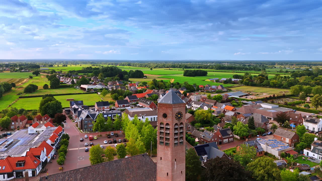 Aerial view of Dutch countryside. A picturesque aerial view showcasing the charm of a Dutch village with green fields and a clock tower under a clear sky