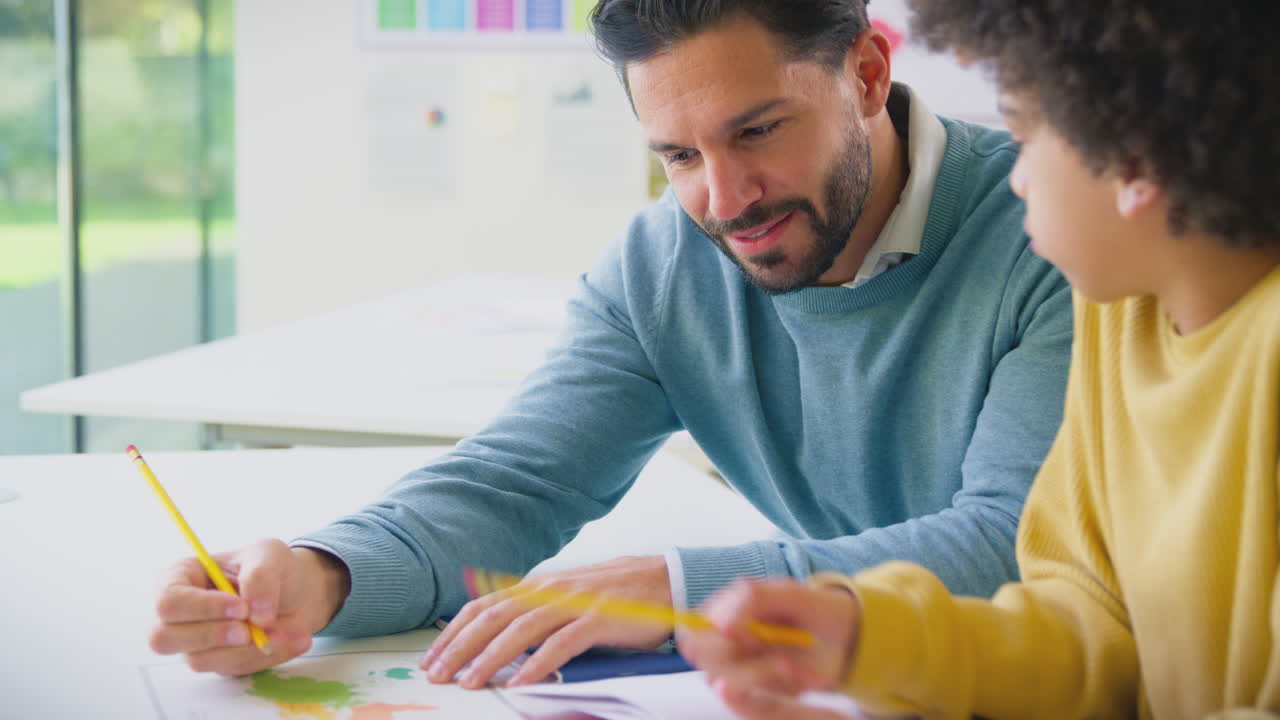 maestro masculino con estudiante en la clase de la escuela sentado en el escritorio mirando el mapa en la lección de geografía
