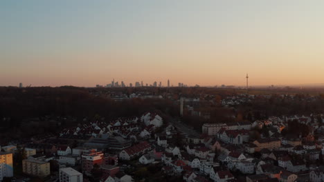 Ferne-Frankfurt-Am-Main-Skyline-Gegen-Dämmerungshimmel.-Absteigende-Drohnenaufnahmen,-Die-Häuser-Und-Straßen-In-Einer-Kleinen-Kurstadt-Enthüllen.-Bad-Vilbel,-Deutschland.