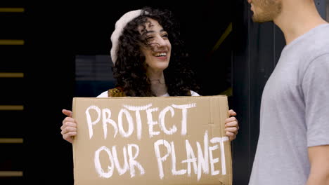 jeune homme parlant avec une jeune femme tenant le conseil de protection de notre planète pour protester