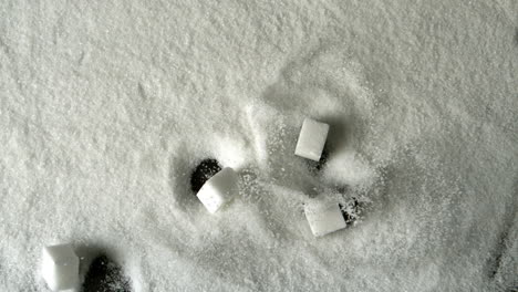 five sugar cubes falling into pile of sugar