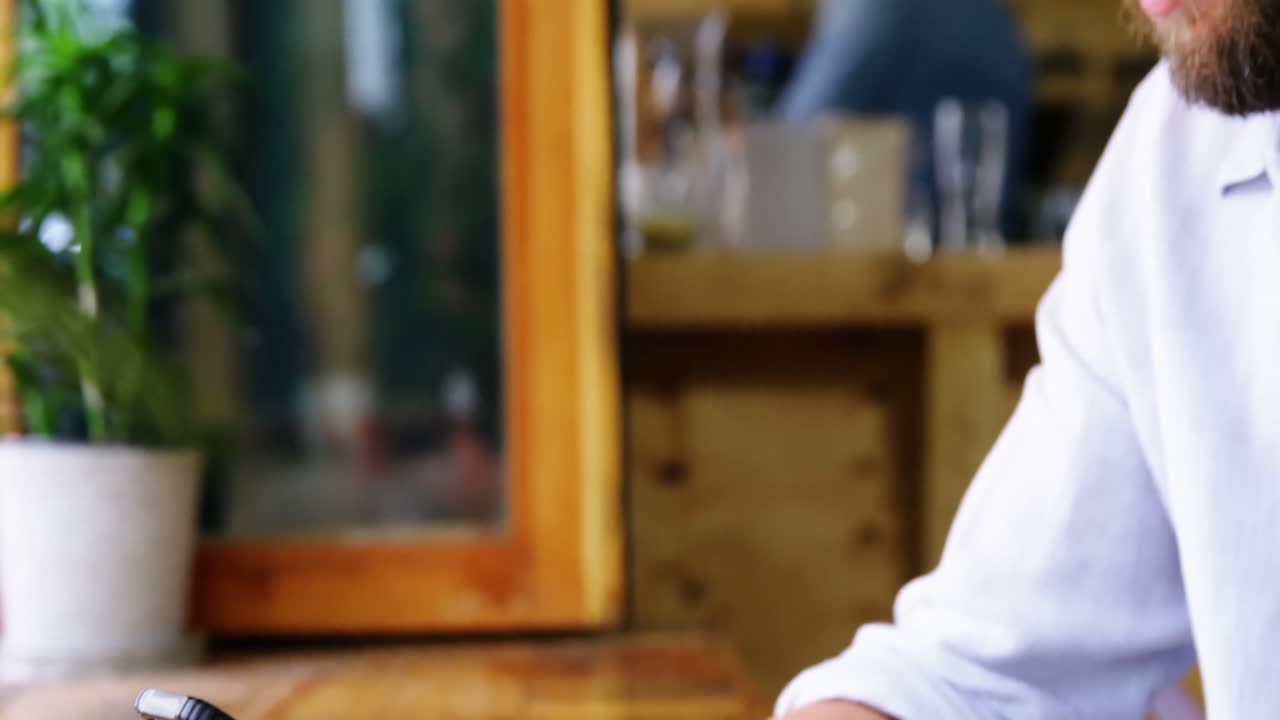 hombre sentado a la mesa y usando el teléfono móvil