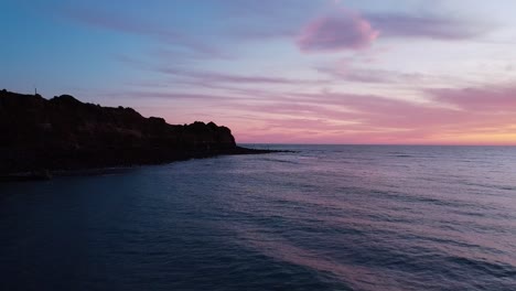 Encanto-Junto-Al-Acantilado:-Nubes-Rosadas-Adornan-Un-Acantilado-Bañado-Por-La-Puesta-De-Sol-En-Un-Cautivador-Metraje-De-Archivo