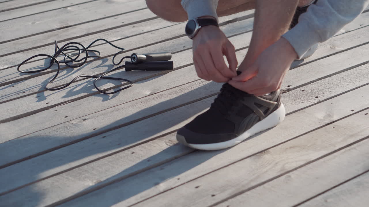 Uomo che si allaccia le scarpe prima di un allenamento con la corda