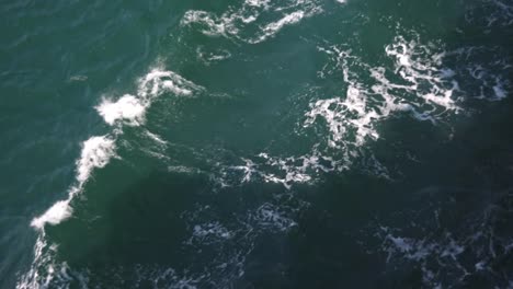 superficie de agua verde turquesa vista desde un ferry con olas en ella