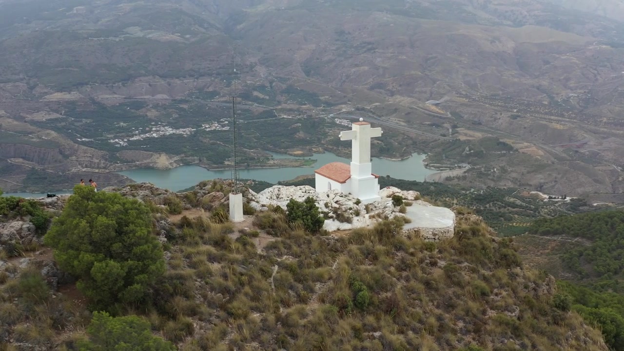 Persone su una collina rocciosa con una piccola chiesa bianca nella Valle di Lecrín, Granada, Spagna.