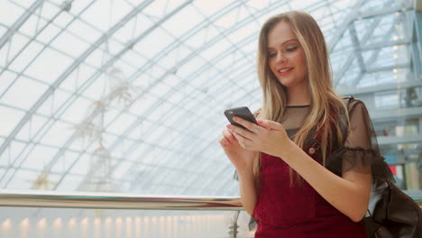 Mädchen-Benutzen-Mobiltelefon,-Verwischen-Das-Bild-Im-Inneren-Des-Einkaufszentrums-Als-Hintergrund.