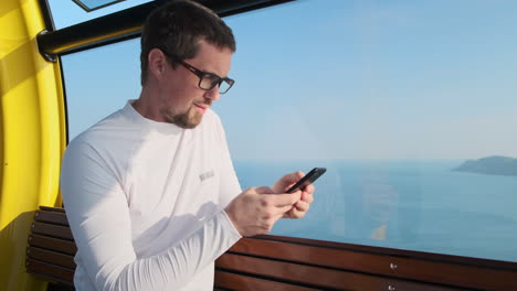 hombre usando un teléfono inteligente en un teleférico
